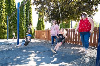 Marcus Larson/News-Register##Teachers Sandra Stevens and Terra Potter push students on swings on the playground at Care for Kids child care center in McMinnville.