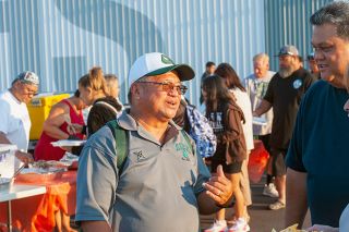 Kirby Neumann-Rea/News-Register##Hawaii native Wendell Say, Linfield Class of 1978, greets friends and visitors at the pre-game dinner for his Aeia High School football team. Danny Paulino, Linfield ‘80, serves dinner in the background.