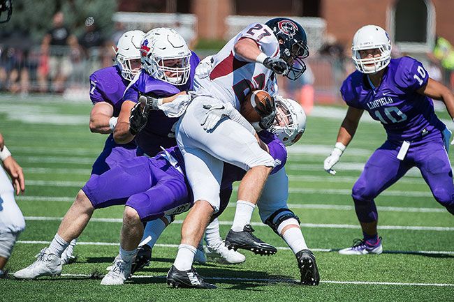 Marcus Larson/News-Register##
Linfield’s Jake Reimer puts a stop tot he run as he tries to wrap up the Chapman ball carrier.