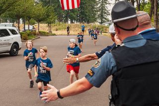 Kirby Neumann-Rea/News-Register##An enthusiastic group of 15 youngsters dashes around the short course at Evergreen Aviation & Space Museum grounds as part of the Champions Run fun. Near the finish line, they exchanged high-fives with law enforcement officers, including Oregon State Trooper Travis Neubauer and Yamhill County Sheriff Tim Svenson.