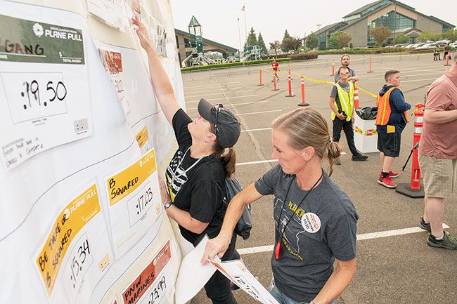 Rusty Rae/News-Register##
Misti Miller of Salem and Gwen Johnson of Sherwood, members of the Plane Pull organizing team, change cards with team times at Saturday s Plane Pull Event. Score cards had velcro on their backs and the two juggled the cards back and forth as new results were reported.