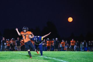 Rusty Rae/News-Register##
With a full moon matching the colors of the Bulldogs jerseys in the background, Orrin Reid gets around Sheridan lineman Hayden Nalley on a quarterback keeper.