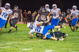 Marcus Larson/For the News-Register##Yamhill-Carlton’s Max Armstrong drags down Amity running back Brandon Aird during a 26-12 victory for the Tigers on Thursday night.