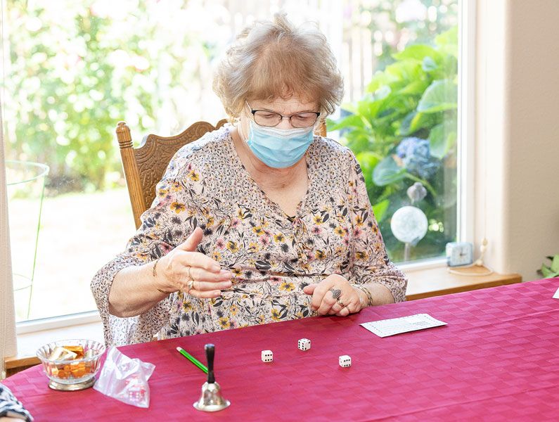 Marcus Larson/News-Register ## Bunco player Patty Sterett rolls the dice during the first game she and her friends have been able to hold since the coronavirus pandemic started.