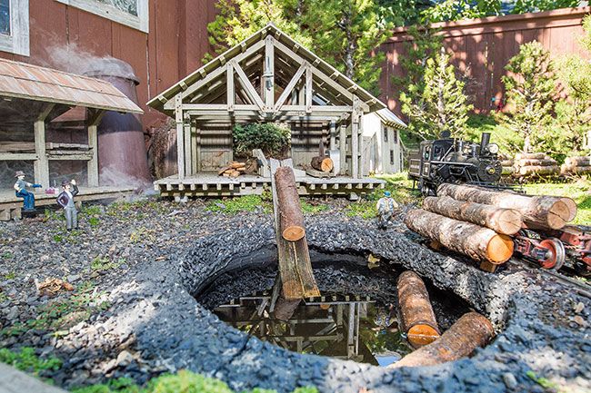 Marcus Larson/News-Register ## Crain’s train dumps logs into a mill pond, then they are pulled  into the mill to be sawn into boards. His garden railroad includes the sound of saws to add authenticity.