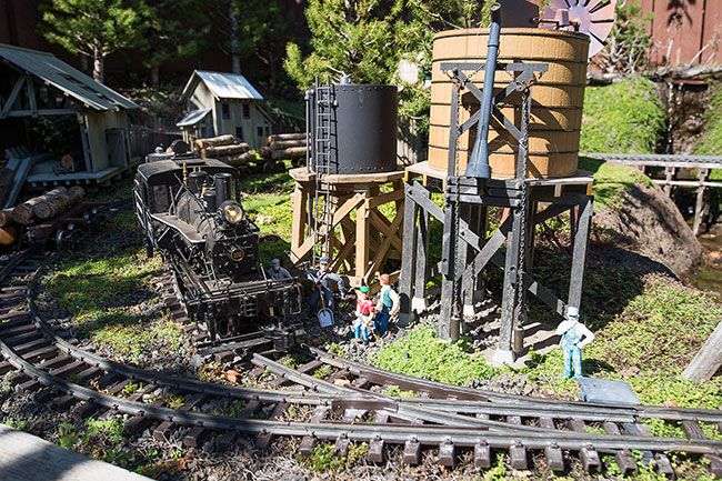 Marcus Larson/News-Register ##
The miniature logging train in Michael Crain’s backyard railroad hauls a load of lumber as it makes its way past several workers.