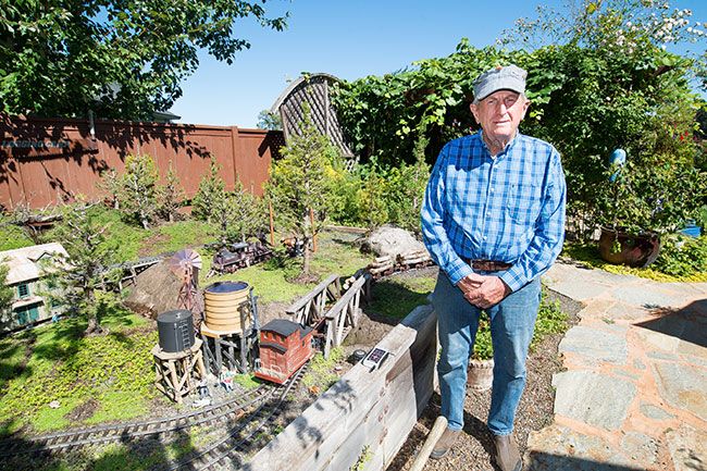 Marcus Larson/News-Register ##
Crain poses next to his backyard train track miniature logging camp. He had trains as a child, and built his garden railroad after moving to McMinnville to live near his grandchildren.