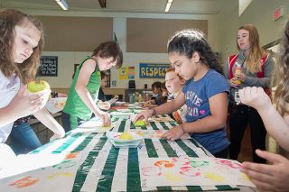 Marcus Larson/News-Register##Jennifer Sandoval, center, and other Kids On The Block students use apple halves to create a painting. Marcus Larson/News-Register##Jennifer Sandoval, center, and other Kids On The Block students use apple halves to create a painting.