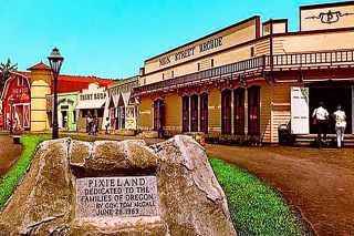 Image: OSU Libraries##A plaque commemorating the dedication of Pixieland by Gov. Tom McCall stands on the park’s main street, with the buildings behind. The rocky lump at the far left, next to the Darigold Barn, is the Darigold Cheese Cave.
