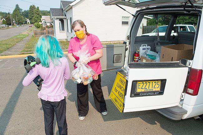 Rusty Rae/News-Register##Devyn Schultz picks up a combination lunch and breakfast offering from Willamina School District food service staff member Becky Snowden at the library on Wednesday.