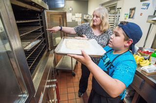 Marcus Larson/News-Register##Cooking class instructor Lynne Shore shows Bodhi Baller where to place a pizza crust in the oven. Marcus Larson/News-Register##Cooking class instructor Lynne Shore shows Bodhi Baller where to place a pizza crust in the oven.