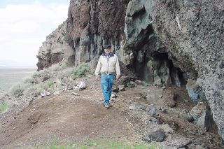 Image: BLM##Bill Cannon, district archaeologist with the BLM, in front of the entrance to Cave No. 5 at the Paisley Caves site, where the 14,300-year-old coprolites were discovered.