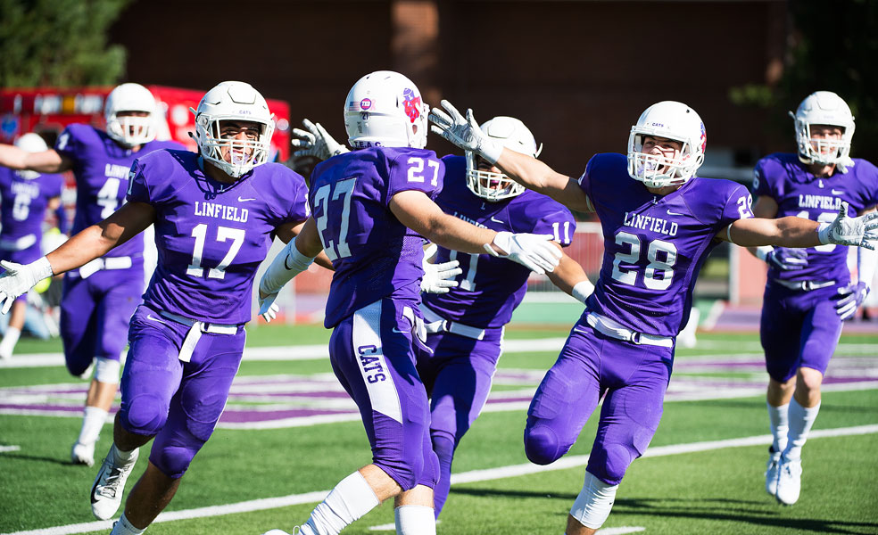 Marcus Larson/News-Register##
Linfield s Keegan Weiss (27) is mobbed by his teammates after his 91-yard kickoff return touchdown.