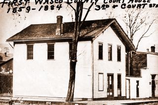 Image: UO Libraries##The original Wasco County Courthouse as it appeared before 1884, when the current courthouse was built. This view shows the sheriff’s office on the lower floor; behind was the jail with no windows on the Third Street side. The narrow door to the right leads to the outside stairway whereby the courtroom on the second floor was reached.