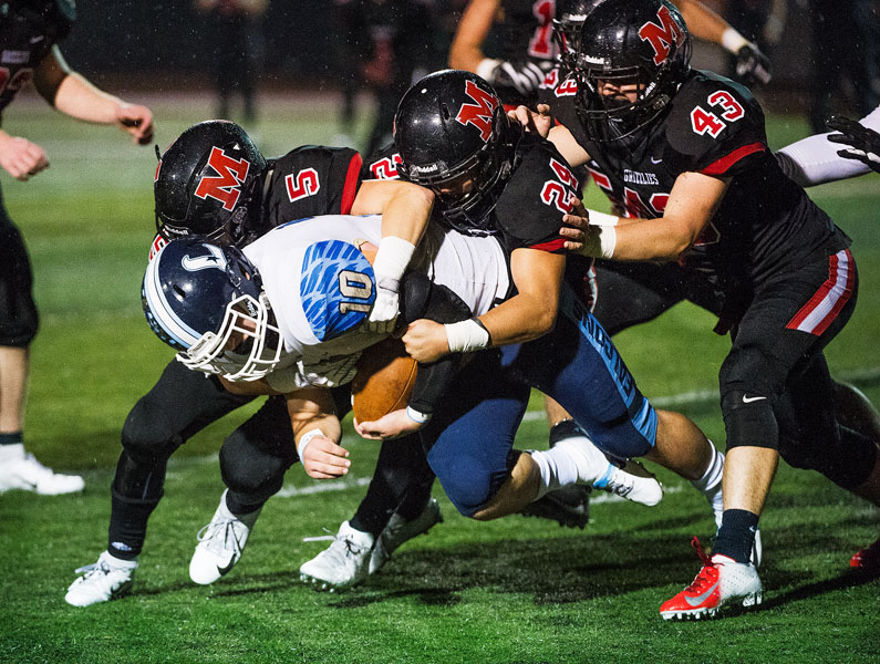 Marcus Larson/News-Register##
McMinnville s Kevin Sullivan (5), Sam Weigel (24) and Jett Hawkins (43) tackle Liberty s Brian Bafaro.