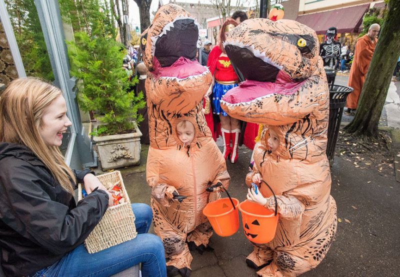 Marcus Larson/News-Register##Twin brothers Everett and Easton Edgerly, dressed as dinosaurs, receive candy from Twist employee Hanna Dobash as they trick or treat on Third Street during the McMinnville Downtown Association’s Safe and Sane Halloween on Monday. Marcus Larson/News-Register##Twin brothers Everett and Easton Edgerly, dressed as dinosaurs, receive candy from Twist employee Hanna Dobash as they trick or treat on Third Street during the McMinnville Downtown Association’s Safe and Sane Halloween on Monday.
