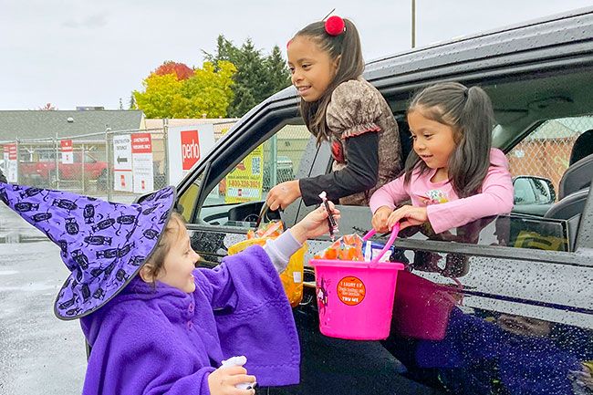 Rachel Thompson/News-Register##Vaida
Slaughter passes out candy to Amairani and Citlali Cabrera,
just one stop on the Lum’s Trunk-or-Treat tour.