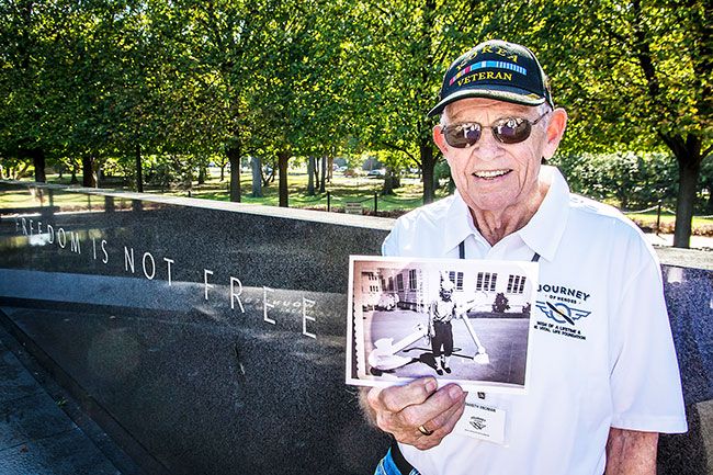 Submitted photo##During his visit to Washington, D.C., memorials, McMinnville’s Ken Vronman holds a photo of himself from his Coast Guard days in the Korean War era. His ship sailed waters off Korea, predicting the weather.