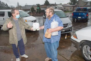 Rusty Rae/News-Register ##
Meals on Wheels volunteer John Davis hands a meal to client Jimmy Wickman, who returned home just in time to receive the delivery. The two men shared a few words in the light rain before Davis drove off to the next stop.