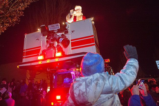 Marcus Larson/News-Register##At the conclusion of the parade on Third Street Friday evening, Santa waves at four-year-old A.J. Volz while waiting to light the town tree.