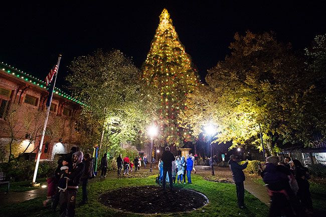 Marcus Larson/News-Register##After the tree lighting ceremony, families line up to take photos in front of the giant sequoia in City Park.