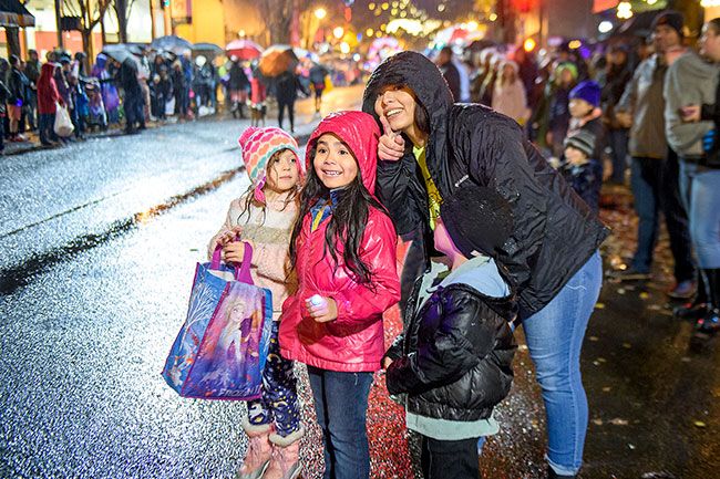 Rusty Rae/News-Register##Leslie De La Rosa points to the fire truck bearing Santa. Watching are Ella, who joined her family from the crowd, and her daughter Mia De La Rosa, and son Noah.