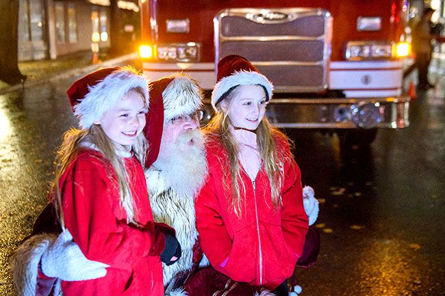 Rusty Rae/News-Register##After Santa arrived and the massive Christmas tree was lit, these two had a chance for a visit with Santa under the cover of a pop-up. The two youngsters are (from the left) Greta Garber, 8, and Hope Brockie, 7. The guy in the red suit with the beard in the middle needs no introduction.