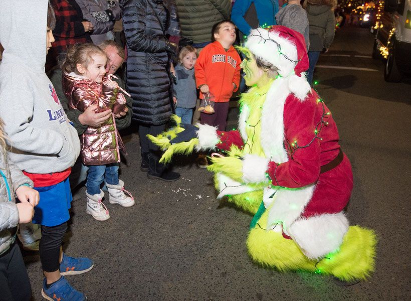 Marcus Larson/News-Register##
Four-year-old Cassandra Peterson smiles with delight as she receives a candy cane from Shasta Ehrhart dressed as the Grinch during the annual McMinnville Christmas parade.