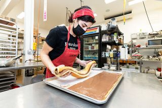 Marcus Larson/News-Register##
Carlton Bakery pastry chef Lisa Bernard rolls a freshly prepared sponge cake with chocolate cream filling made with Valrhona chocolate, which is made near Bernard’s childhood home in the Rhône Valley of France. When decorated, the cake will resemble a log, a French Christmas tradition called “Bûche de Noël.”
