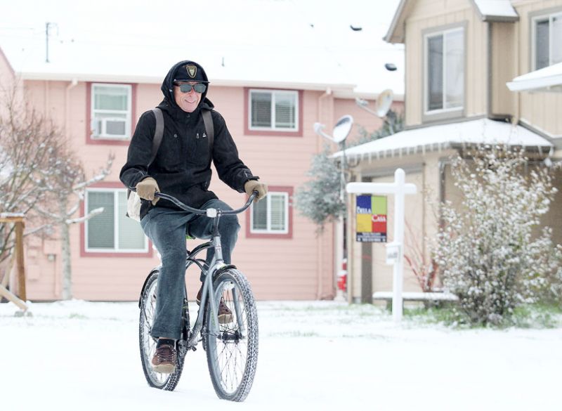 Rockne Roll/News-Register##A man rides his bicycle through the snow along Southwest Washington Street.