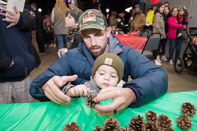 Marcus Larson/News-Register##
Christopher Kluser of Amity helps his son Jaxon, 2, with making a pine
cone ornament.