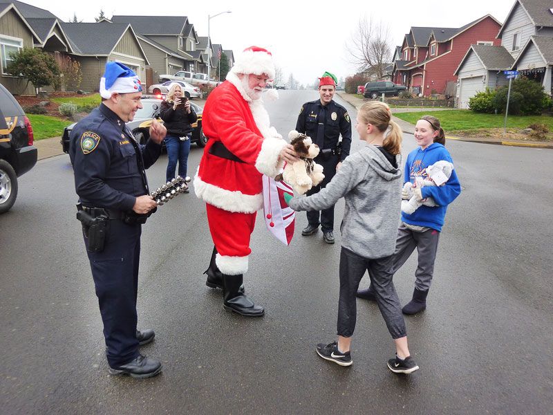 Starla Pointer/News-Register##
Santa hands stuffed animals to Elizabeth Hetzler and Katelyn Jacobs during the Carlton police department s holiday patrol. Officer drove around town meeting kids on Saturday, Dec. 16.