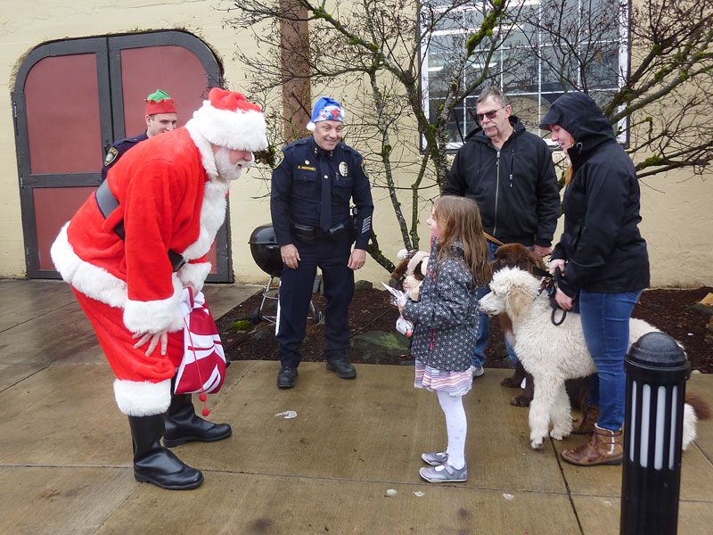 Starla Pointer / News-Register##
Abigail Wheeler, 6, tells Santa about herself when they meet on Monroe Street in Carlton. Police Chief Kevin Martinez, center, reminded kids that Santa wants them to do nice things for others.