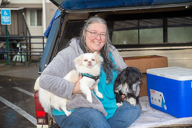 Rusty Rae/News-Register##Candyce Banta with her dogs, Falkor and Ms. Daisy, relax on the tailgate of her truck, where they once lived. They recently moved into an apartment with the help of Champion Team and YCAP.