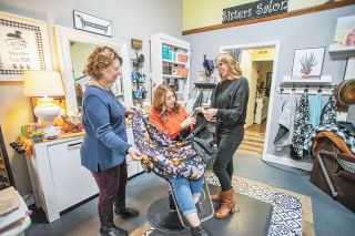 Rachel Thompson/News-Register##Maddy Mastropoalo, center, dons a Hairapy Cape while her aunt, Julie Schreiner, and mother, Heidi Mastropoalo, prepare to work on her hair at their salon, Sisters, in McMinnville. All three women are hairdressers. Heidi Mastropoalo invented the cozy cape to keep customers warm and comfortable.
