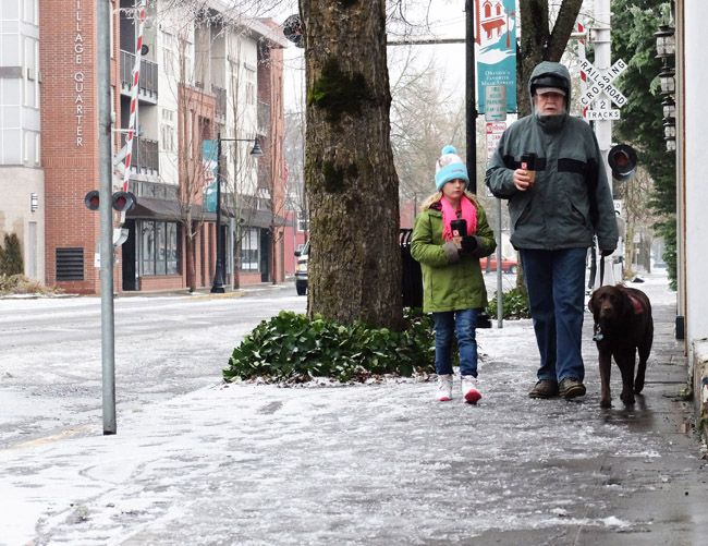 Rockne Roll/News-Register##
From left, nine-year-old Mariah Osborn, her grandfather Mike Day and Day s dog Suh trudge through the slush along Northeast Third Street in McMinnville Monday morning as ice and cold blanketed the area.