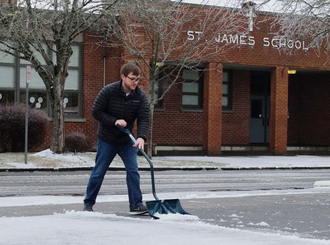 Rockne Roll/News-Register##
Joel Bowder of Mountain View Oral Surgery shovles slush from his office parking lot Monday, Jan. 4. McMinnville School District and St. James Catholic School (background) were operating on two-hour delay Monday, other schools throughout the Yamhill Valley were closed Monday due to the icy conditions.