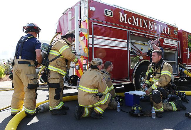 Rockne Roll/News-Register ##
McMinnville firefighters rehydrate and replenish their oxygen takes in the shade of an engine while fighting the house fire at 1820 SW Alexandria St. in McMinnville on Friday afternoon.