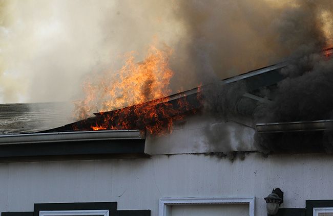 Rockne Roll/News-Register ##
Flames emerge from the caving-in roof of  the house at 182 SW Alexandria St. in McMinnville, which caught fire Friday afternoon.