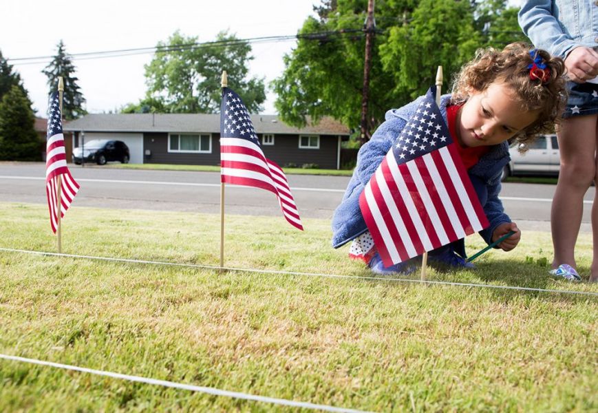 Rockne Roll/News-Register##
Rachel Wilkins, 5, plants an American flag in a row with others Friday as McMinnville Christian Academy student set up their Memorial Day flag display. More than 5,000 flags were erected in the school s front lawn along Baker Creek Road -- one for each Oregonian killed in military service since World War I.