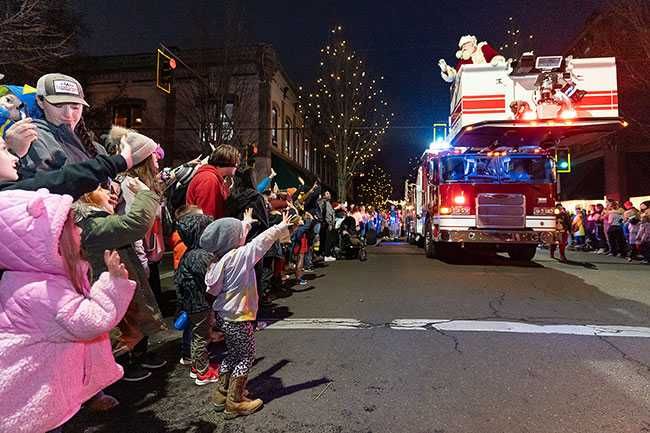 Marcus Larson/News-Register##Children wave to Santa as he arrives on Third Street during Friday s Santa Parade.