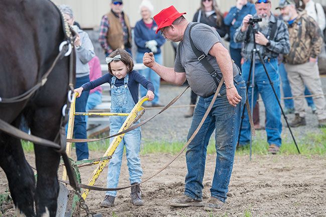 Rusty Rae/News-Register##Duane Van Dyke of Carlton encourages his granddaughter, Imogen, 7, as she holds a plow pulled by horses Clare and Sophy during competition at Saturday s Yamhill Valley Heritage Center s Farm Fest.