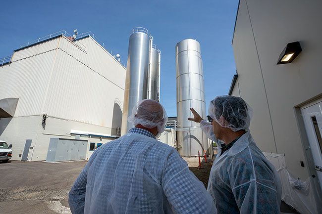 Rachel Thompson/News-Register##Organic Valley company officers Mark Pfeiffer and CEO Jeff Frank look at the huge storage tanks saved from the fire and new ones added in the reconstruction of the McMinnville plant. The company ordered additional tanks soon after the April 2021 blaze, which helped expedite rebuilding, allowing it to return to dry milk powder processing a year ago.