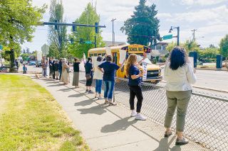 Starla Pointer/News-Register##McMinnville School District classified employees, and one canine supporter, rally with signs in front of the District Office, on Lafayette Avenue Wednesday, as a school bus drives by.