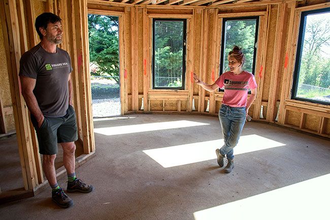 Rusty Rae/News-Register##Jody Hall compliments her husband, Terry, on the large dining room in the turret of their latest home, built to resemble a castle. The master bedroom occupies the second floor of the turret.