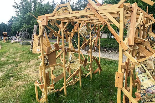 Kirby Neumann-Rea/News-Register##“Tunnel” is made of scrap wood and adorned with newsprint designed “to melt away,” according to art major Marissa Nagano of Hawaii. The work stands in a row of art walk sculptures along the Linfield University wellness trail near Keck Avenue.