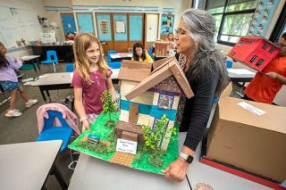 Rachel Thompson/News-Register##St. James School second/third-grade teacher Donna Carlisle helps Adelynn Moore lift the student’s model of the Cozine House. The 1892 building started life as the home of Samuel Cozine, and now holds the McMinnville Downtown Association office.