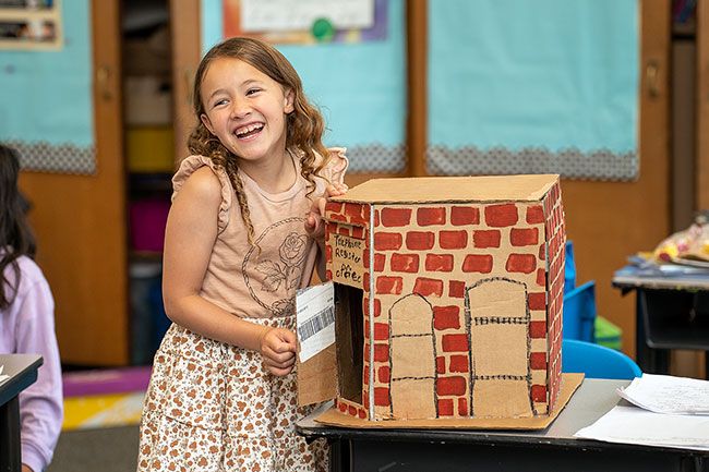Rachel Thompson/News-Register##Eleanor Field delightedly tells her classmates about the brick building that once held a newspaper office and is now the site of Two Dogs Taphouse. She used her ingenuity to create a door handle with hot glue.