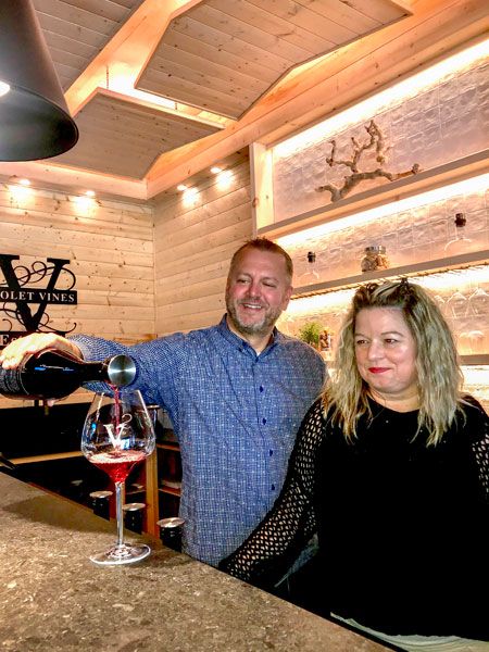 Kirby Neumann-Rea/News-Register##Violet Vines’ Brian Zawada, with his wife, April, pours estate Pinot Noir beneath white pine cutouts formed in shapes of the blocks, or growing  areas, at their vineyard.
