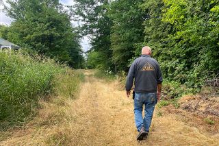 Starla Pointer/News-Register##Carlton City Council member Grant Erickson checks out the tall grass and brush on the old railroad grade trail through Carlton. He and other volunteers will clean up the area  July 8 to make it safer and less vulnerable to fire danger.
